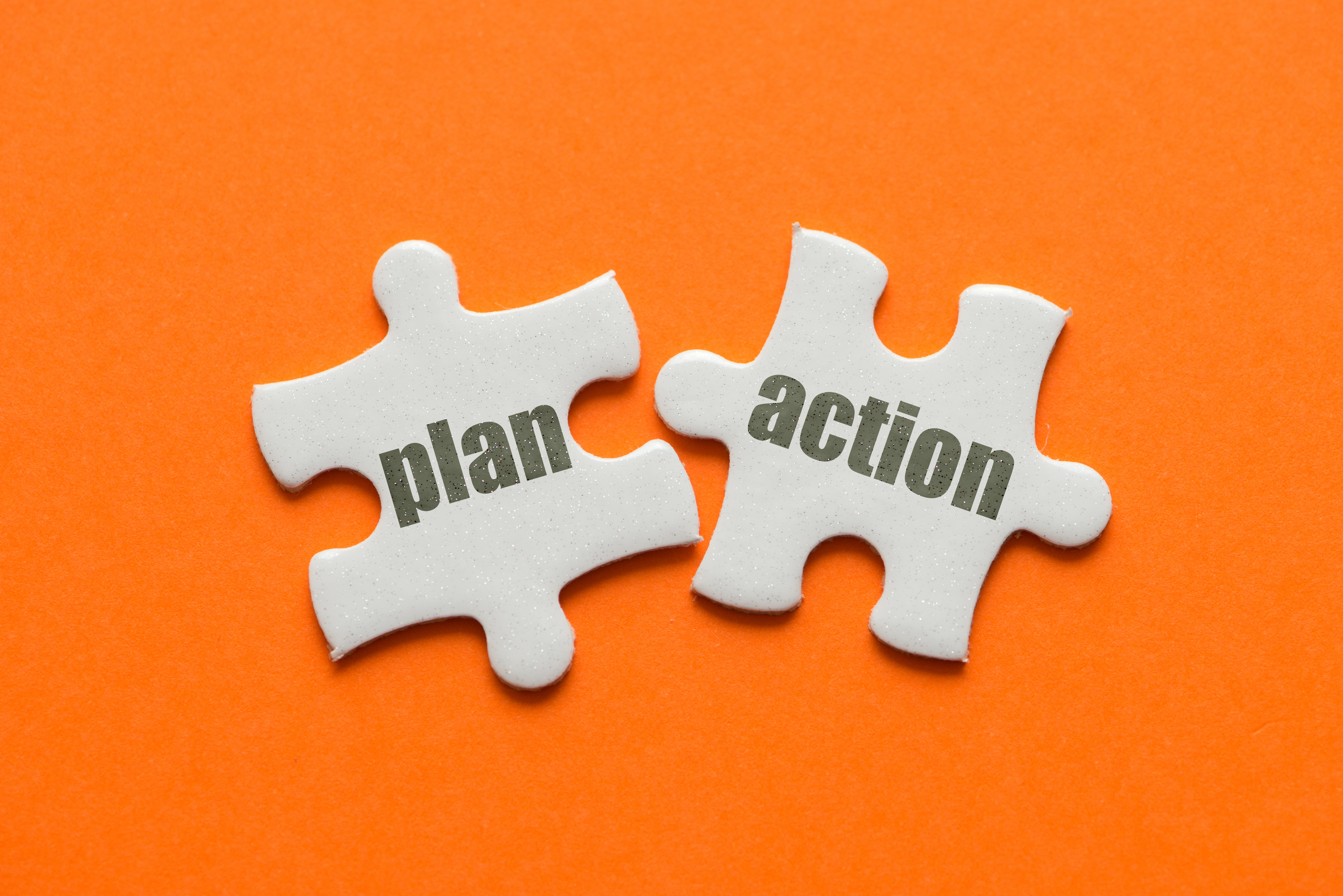 The word Plan Action on two matching puzzle on orange background.